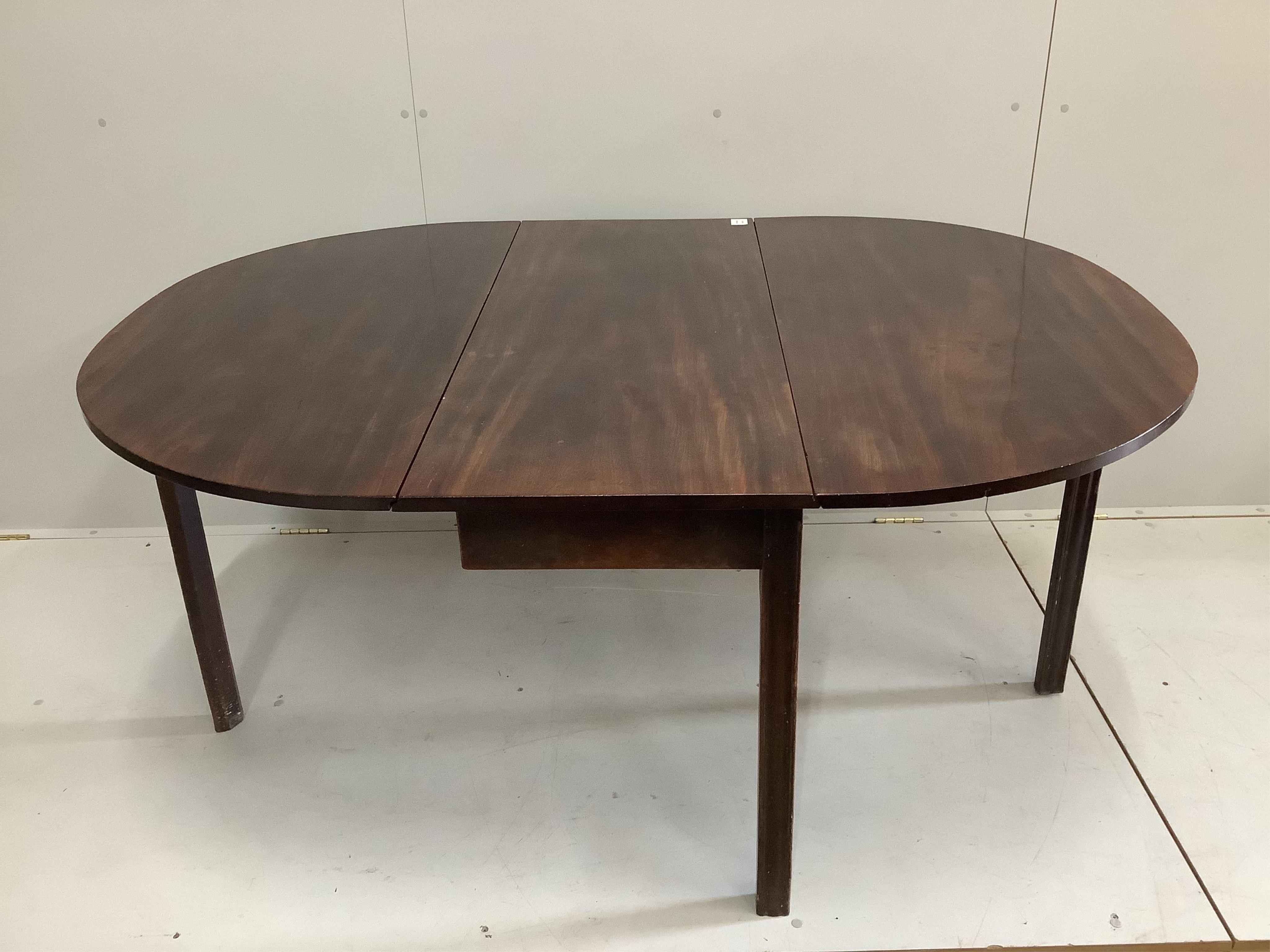 A George III oval mahogany drop leaf extending dining table, on pad feet, width 114cm, 156cm extended, height 70cm. Condition - fair